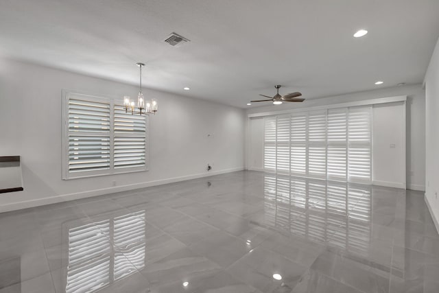 unfurnished living room featuring ceiling fan with notable chandelier and a wealth of natural light