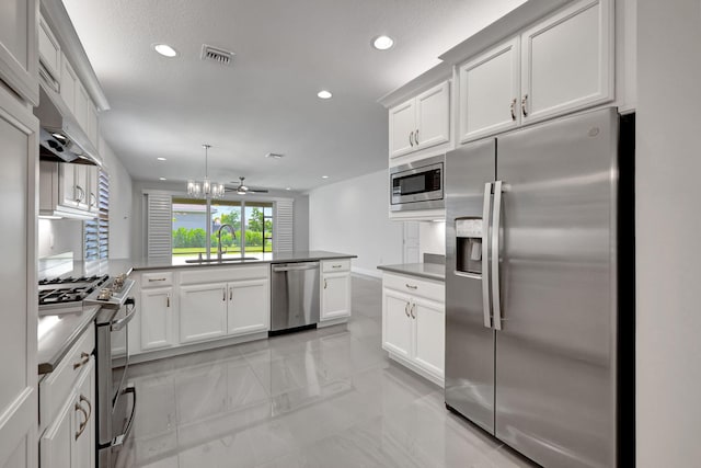 kitchen with white cabinets, hanging light fixtures, ceiling fan, kitchen peninsula, and stainless steel appliances