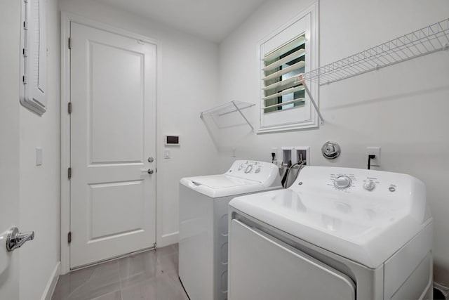 laundry room featuring electric panel, light tile patterned floors, and washer and dryer