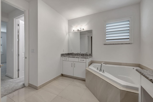 bathroom with tiled tub, tile patterned flooring, and vanity