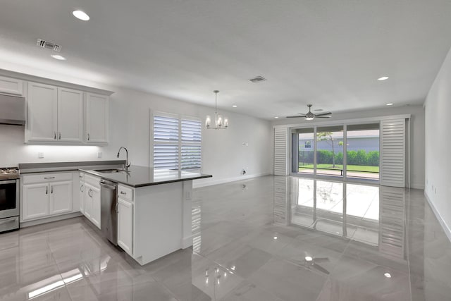 kitchen featuring pendant lighting, ceiling fan with notable chandelier, sink, appliances with stainless steel finishes, and white cabinetry