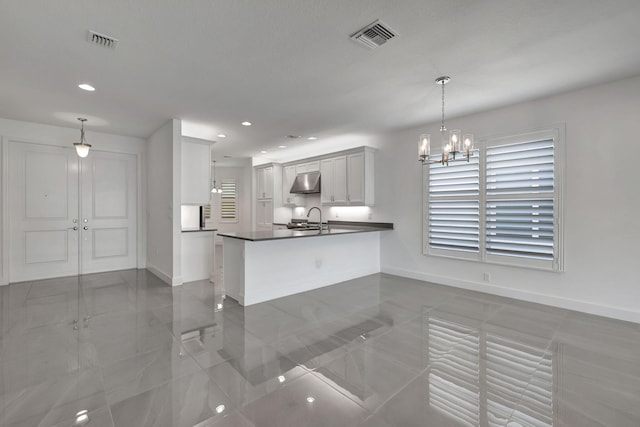 kitchen featuring kitchen peninsula, sink, pendant lighting, a notable chandelier, and white cabinets