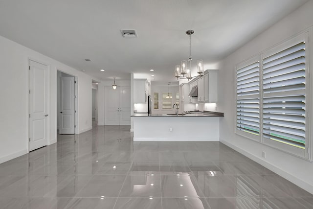 kitchen with pendant lighting, white cabinets, sink, a notable chandelier, and kitchen peninsula