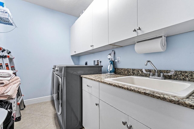 laundry area with sink, cabinets, a textured ceiling, light tile patterned floors, and washer and clothes dryer