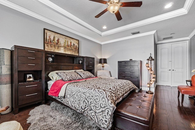 bedroom with dark hardwood / wood-style flooring, ornamental molding, ceiling fan, a raised ceiling, and a textured ceiling