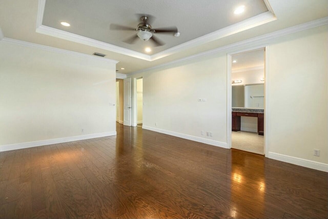 empty room with dark hardwood / wood-style floors, ornamental molding, a raised ceiling, and ceiling fan