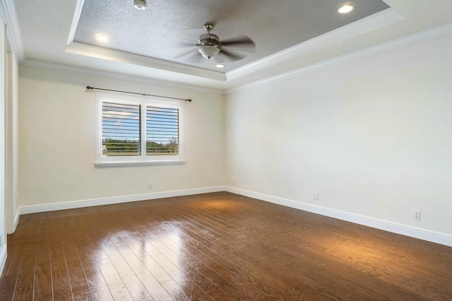 empty room with a raised ceiling, ceiling fan, ornamental molding, and dark hardwood / wood-style flooring