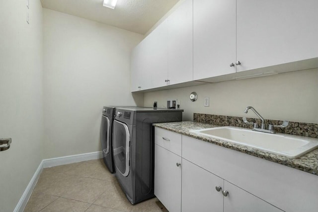 clothes washing area with sink, light tile patterned floors, cabinets, and independent washer and dryer