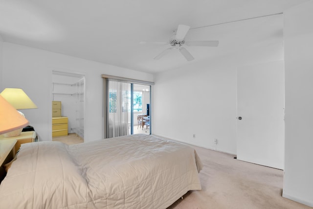 bedroom with a walk in closet, a closet, light colored carpet, and ceiling fan