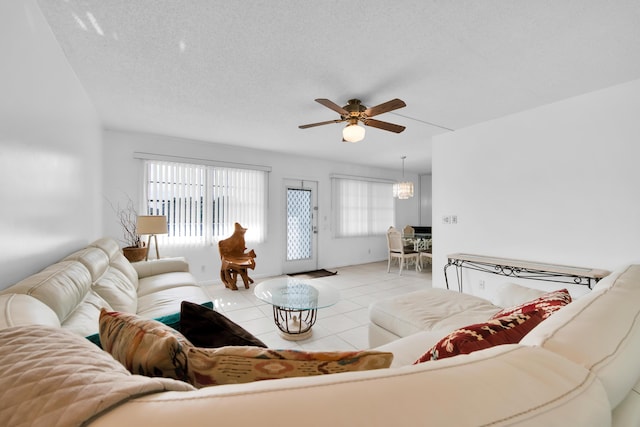 tiled living room featuring ceiling fan with notable chandelier and a textured ceiling