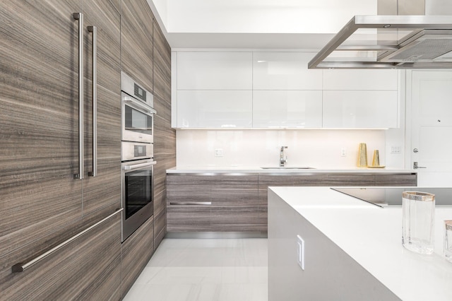 kitchen with black electric stovetop, double oven, sink, exhaust hood, and white cabinetry