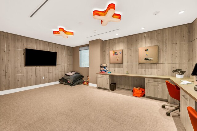 carpeted office featuring built in desk and wooden walls