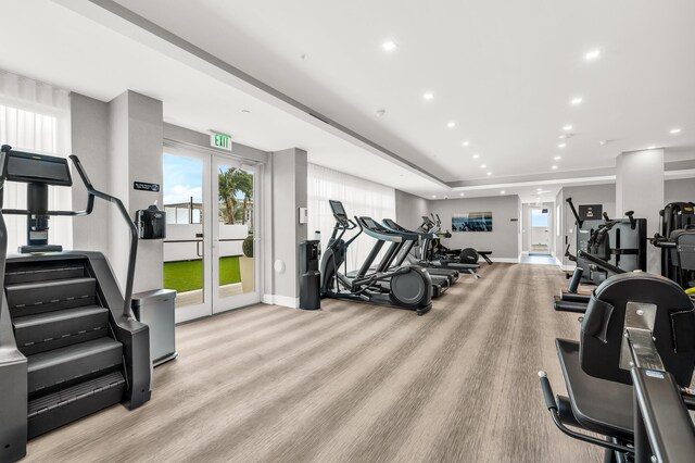 exercise room with light wood-type flooring and french doors