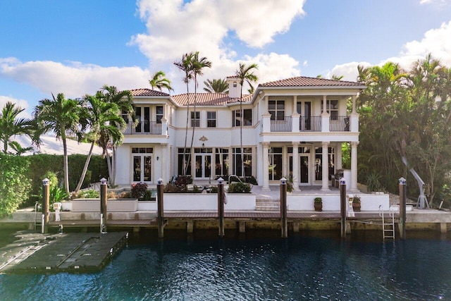 rear view of property with french doors, a balcony, and a water view