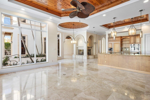 unfurnished living room featuring ceiling fan, a raised ceiling, wood ceiling, and ornamental molding