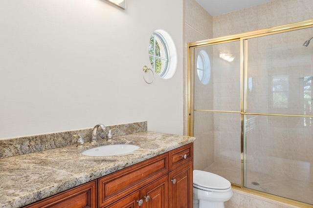 bathroom featuring vanity, toilet, and a shower with door