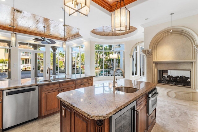 kitchen with sink, stainless steel appliances, wine cooler, pendant lighting, and a kitchen island with sink