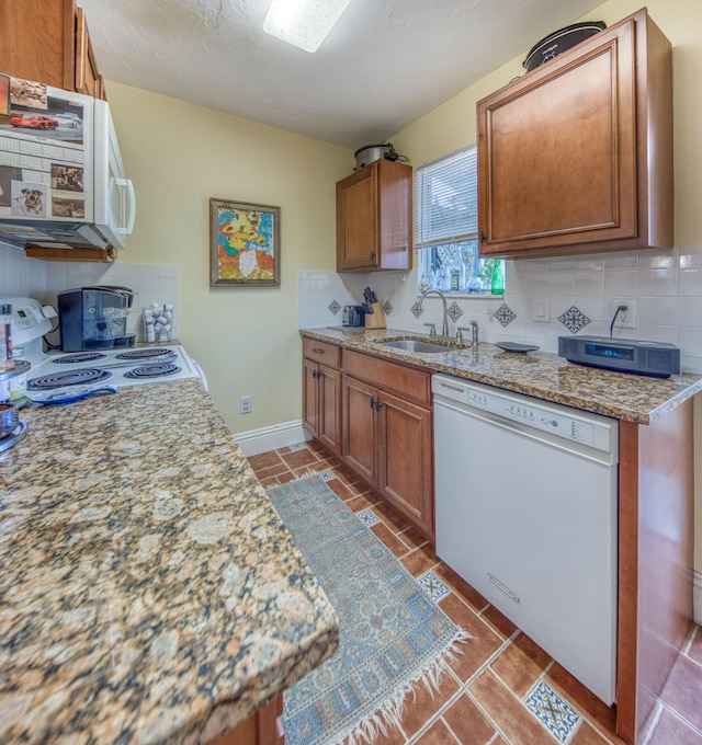 kitchen featuring light stone countertops, white appliances, sink, and tasteful backsplash