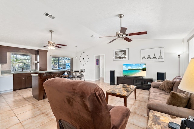 tiled living room featuring ceiling fan, sink, lofted ceiling, and a textured ceiling