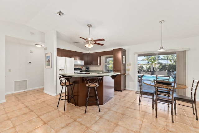 kitchen featuring white appliances, lofted ceiling, ceiling fan, a kitchen bar, and dark brown cabinetry