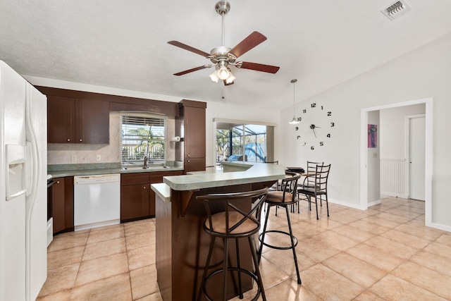 kitchen with white appliances, dark brown cabinetry, vaulted ceiling, ceiling fan, and sink