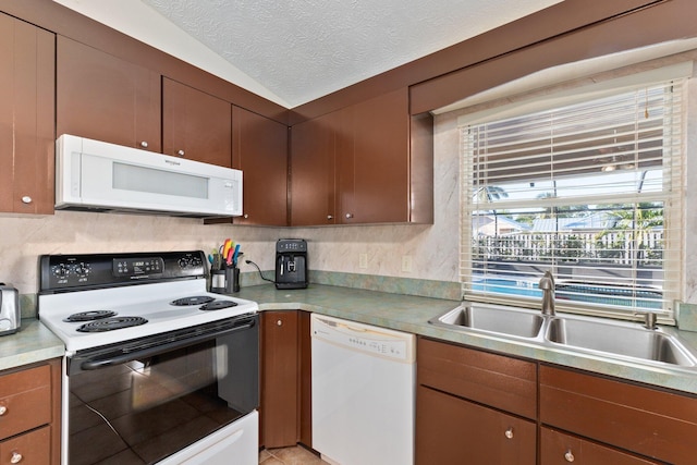 kitchen featuring a textured ceiling, decorative backsplash, white appliances, and sink