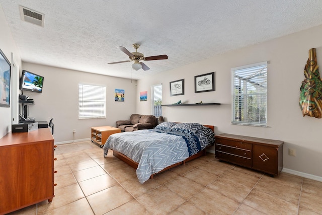 bedroom with a textured ceiling, ceiling fan, and light tile patterned flooring