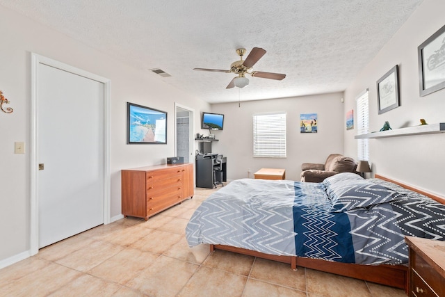 bedroom featuring ceiling fan, light tile patterned flooring, and a textured ceiling