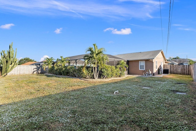 view of yard featuring glass enclosure and central AC unit