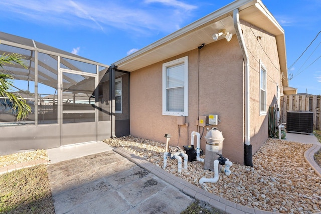 view of home's exterior with glass enclosure and central air condition unit