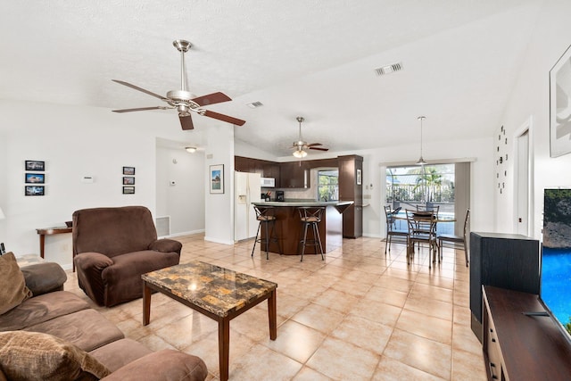 living room with ceiling fan, light tile patterned floors, and lofted ceiling