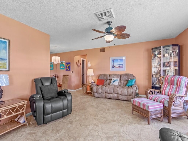 living room featuring ceiling fan with notable chandelier and a textured ceiling