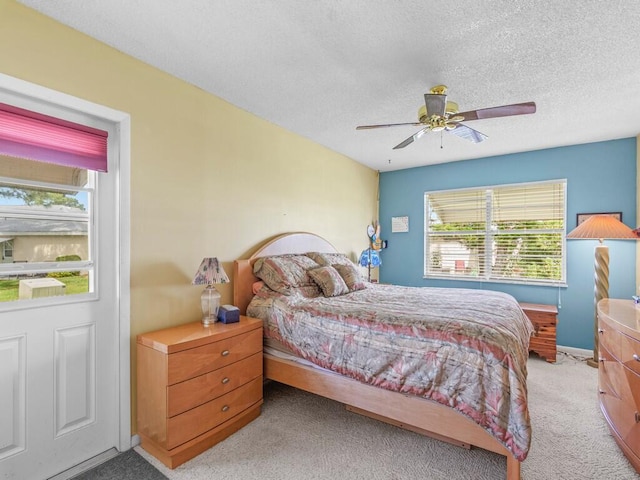 bedroom featuring light carpet, a textured ceiling, and ceiling fan