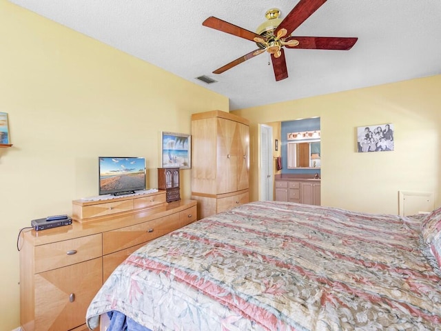 bedroom with ensuite bathroom, ceiling fan, and a textured ceiling