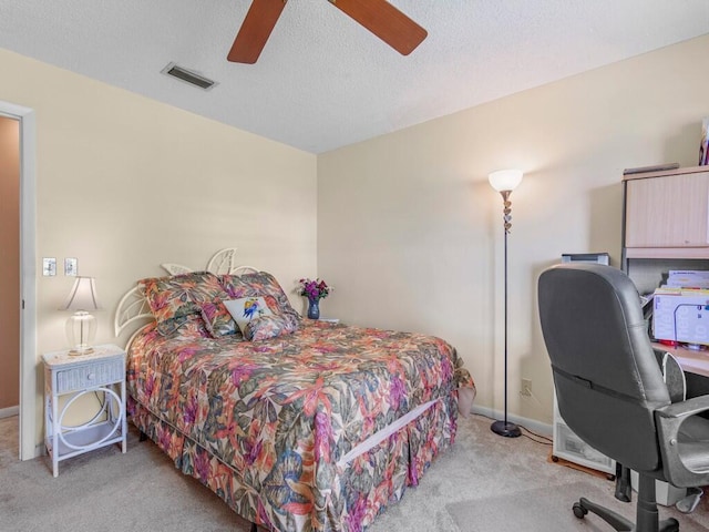 carpeted bedroom featuring ceiling fan and a textured ceiling