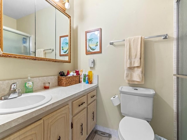 bathroom with a shower with door, vanity, and toilet