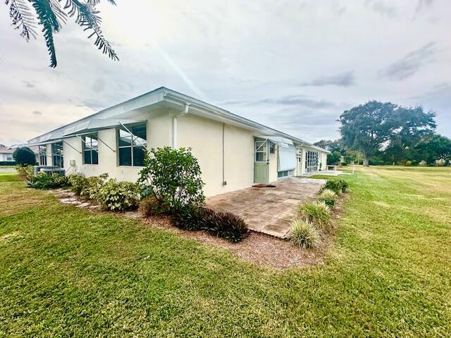 view of property exterior with a yard and a patio