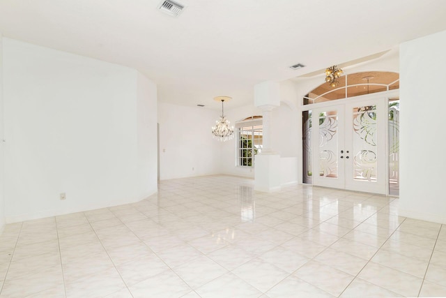 tiled spare room with a notable chandelier and french doors