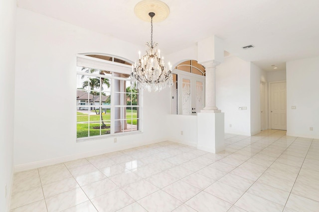 tiled spare room with a chandelier and ornate columns