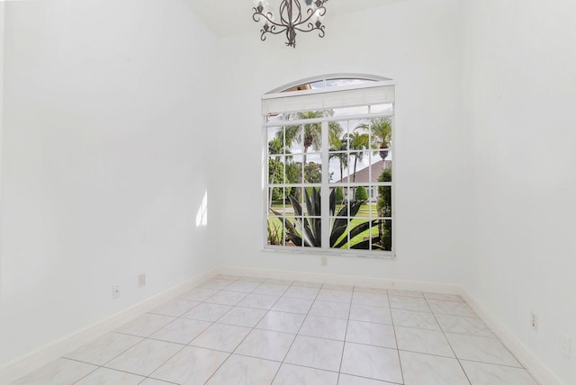 spare room with light tile patterned floors and a chandelier