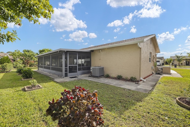 rear view of property with a sunroom, a lawn, and central AC