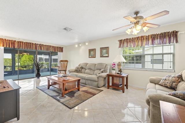 tiled living room with ceiling fan, a healthy amount of sunlight, and a textured ceiling