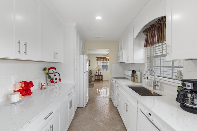 kitchen featuring light stone countertops, white appliances, sink, and a wealth of natural light