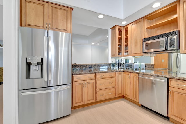 kitchen with stainless steel appliances, light hardwood / wood-style flooring, and stone countertops