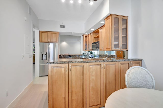 kitchen featuring kitchen peninsula, stainless steel fridge with ice dispenser, and dark stone countertops