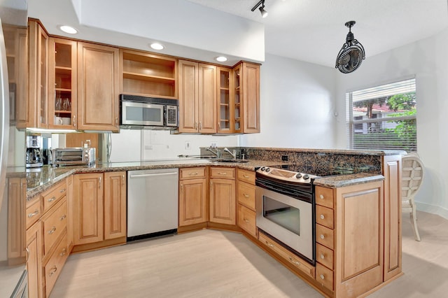 kitchen with stone countertops, light wood-type flooring, kitchen peninsula, and appliances with stainless steel finishes