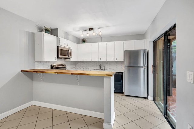 kitchen featuring backsplash, sink, butcher block countertops, white cabinetry, and stainless steel appliances