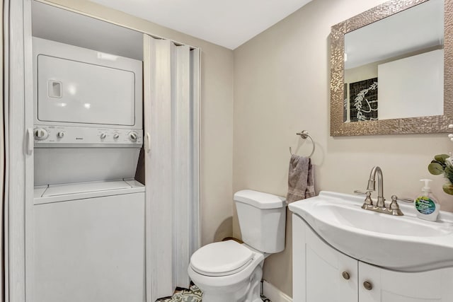 bathroom featuring stacked washer / dryer, vanity, and toilet