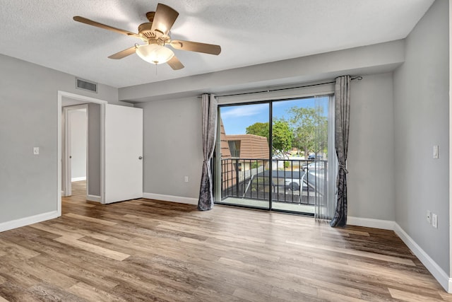 empty room featuring ceiling fan, light hardwood / wood-style floors, and a textured ceiling