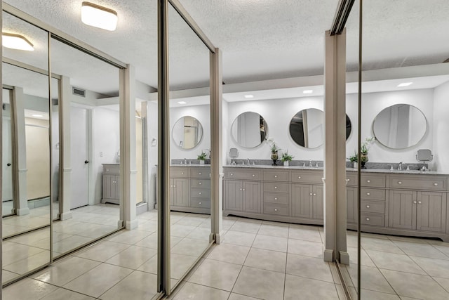 bathroom with tile patterned flooring, vanity, and a textured ceiling